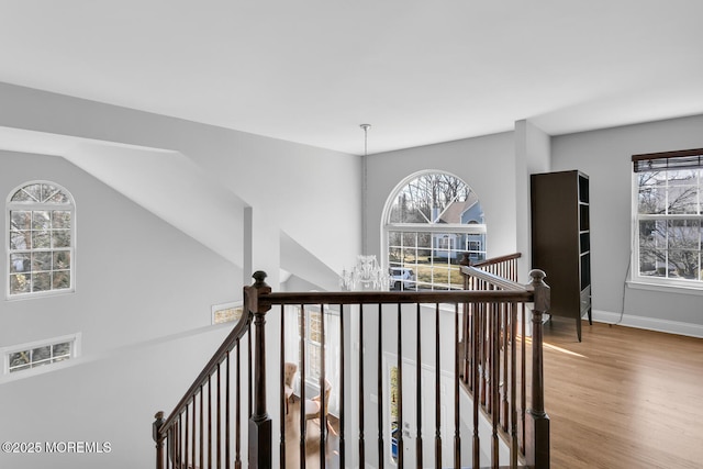 corridor with an inviting chandelier, plenty of natural light, an upstairs landing, and wood finished floors