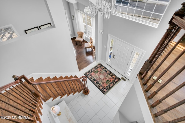 tiled entryway featuring a high ceiling, stairs, and a chandelier