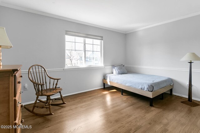 bedroom with crown molding, baseboards, and wood finished floors