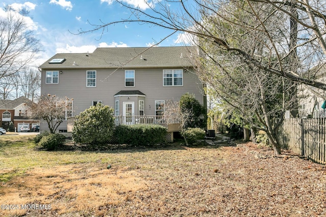 back of property with fence, a lawn, and a wooden deck