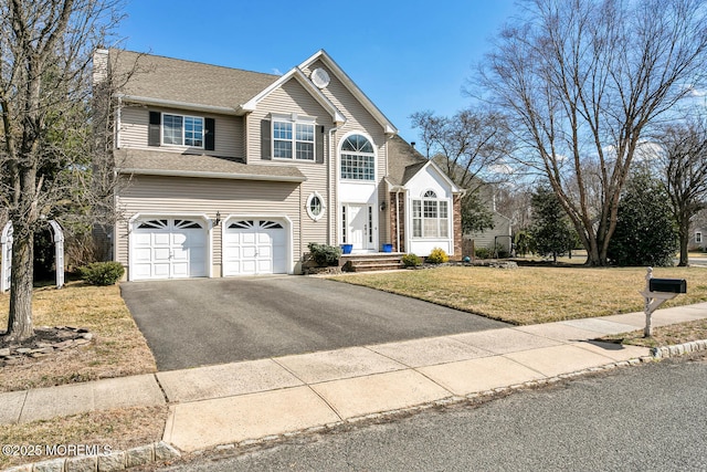 traditional-style home with aphalt driveway, a front lawn, and an attached garage