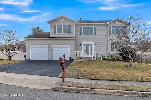 traditional home with an attached garage, fence, aphalt driveway, and a front yard