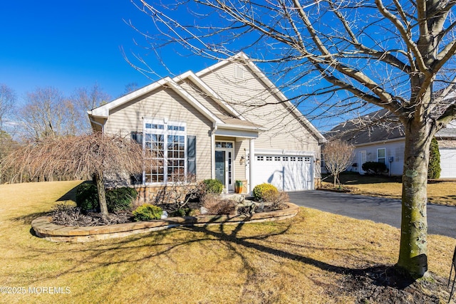 traditional-style home featuring a garage, aphalt driveway, and a front yard