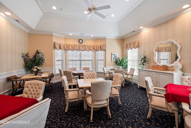 dining space featuring wallpapered walls, wainscoting, ornamental molding, a tray ceiling, and dark colored carpet