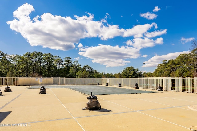 view of tennis court with a patio area, a community pool, and fence