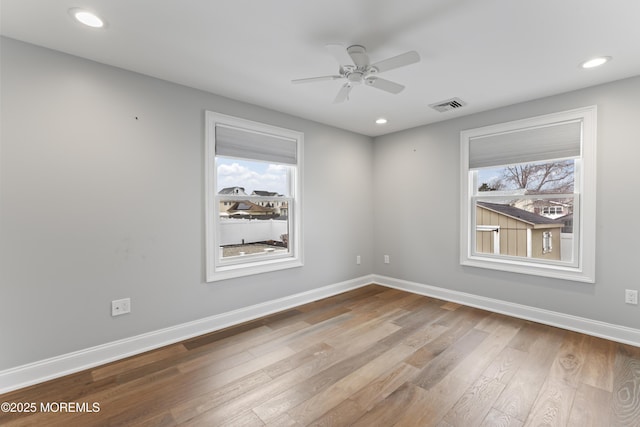 spare room featuring a wealth of natural light, visible vents, baseboards, and wood finished floors