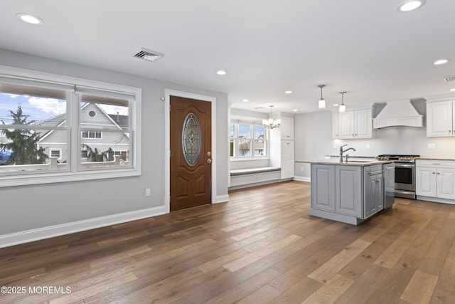 kitchen featuring premium range hood, a sink, visible vents, white cabinetry, and stainless steel gas stove