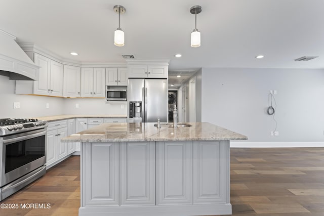 kitchen featuring stacked washer and dryer, custom range hood, dark wood-style flooring, stainless steel appliances, and a sink