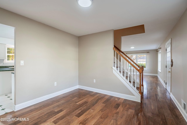 unfurnished room with visible vents, stairs, baseboards, and wood finished floors