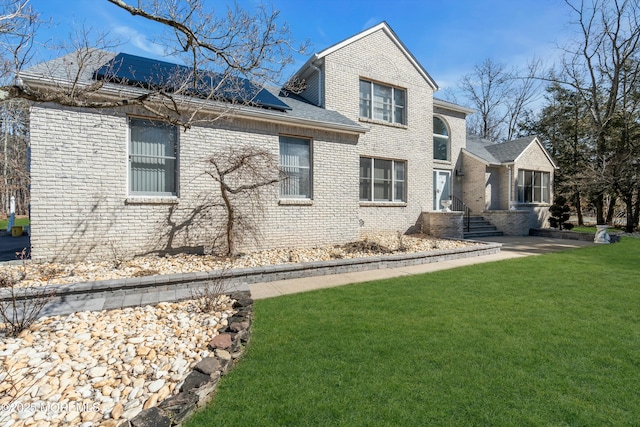 exterior space with solar panels, a yard, and brick siding