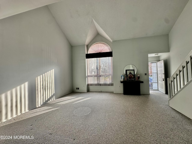 unfurnished living room featuring carpet floors, stairs, high vaulted ceiling, and a textured ceiling