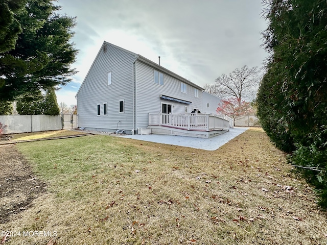 rear view of property featuring a lawn and fence