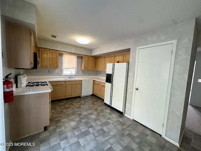 kitchen featuring a textured ceiling, white appliances, a sink, visible vents, and light countertops