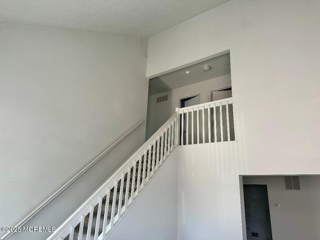 staircase with a textured ceiling and visible vents