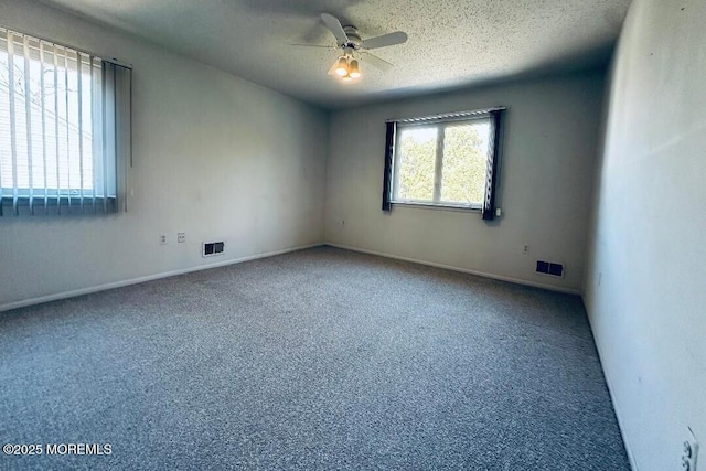 carpeted empty room with ceiling fan, visible vents, and a textured ceiling