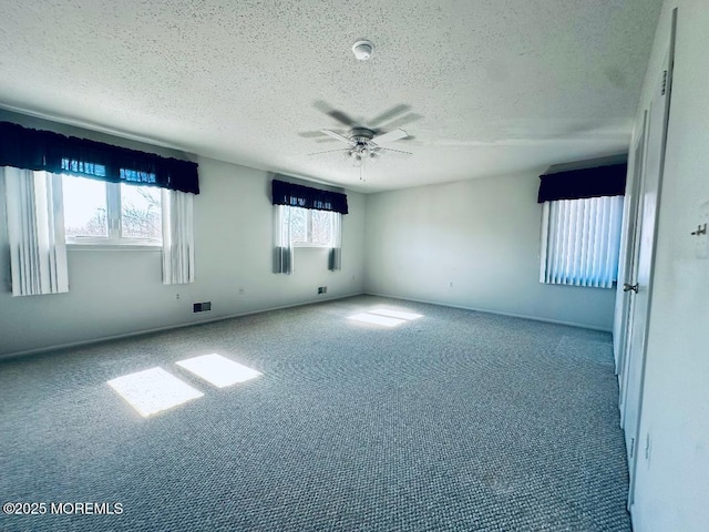 unfurnished room with carpet floors, visible vents, a textured ceiling, and a ceiling fan