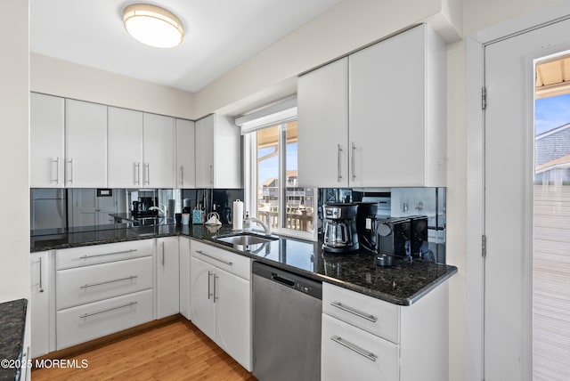 kitchen with a sink, light wood-style floors, white cabinets, dishwasher, and dark stone countertops