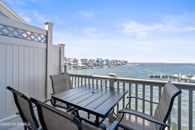 balcony featuring outdoor dining space and a water view