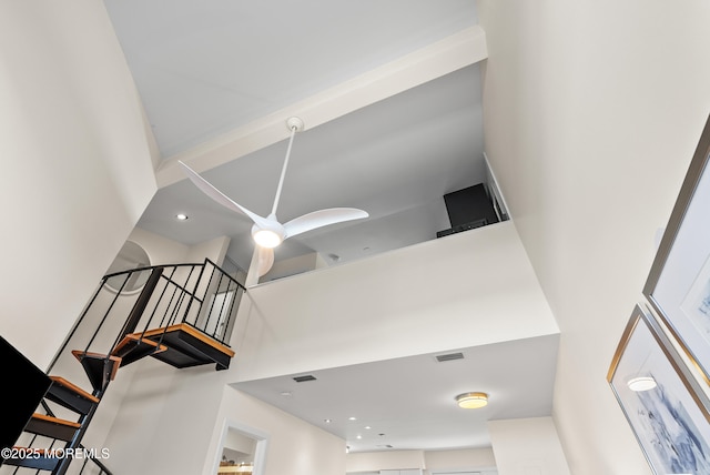 stairs featuring ceiling fan, a high ceiling, and visible vents