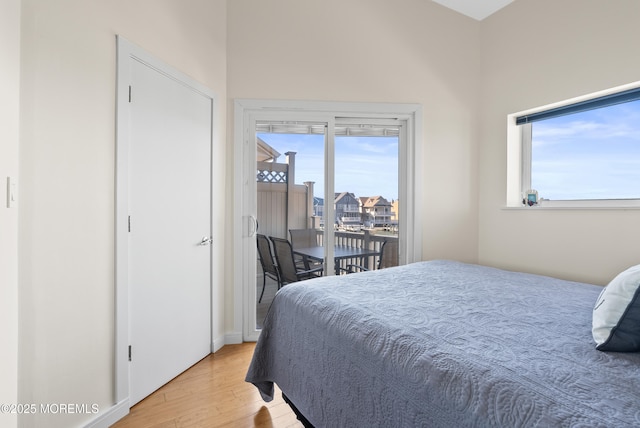 bedroom with light wood-type flooring, access to exterior, and multiple windows