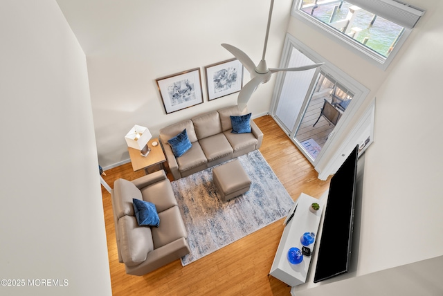 living room featuring ceiling fan, baseboards, and wood finished floors