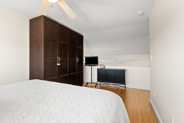 bedroom featuring a ceiling fan, vaulted ceiling, baseboards, and wood finished floors