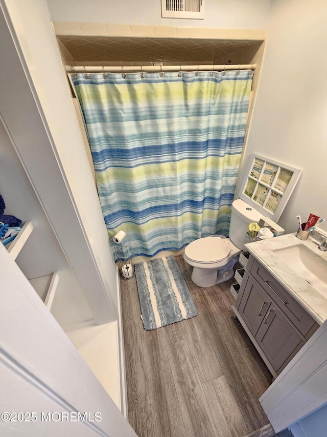 bathroom with vanity, a shower with curtain, wood finished floors, visible vents, and toilet