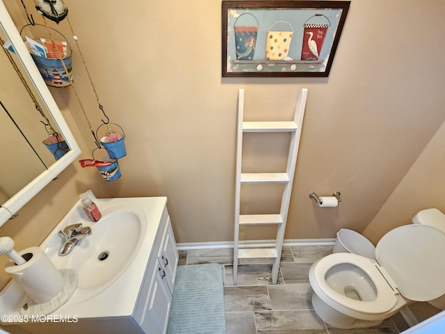 half bathroom with toilet, vanity, and baseboards