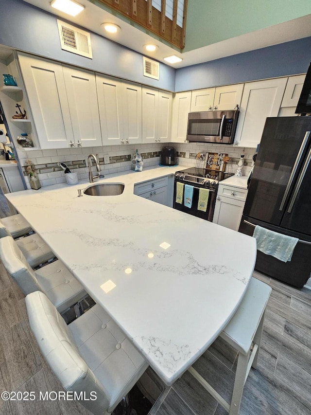 kitchen featuring stainless steel microwave, visible vents, freestanding refrigerator, and electric range