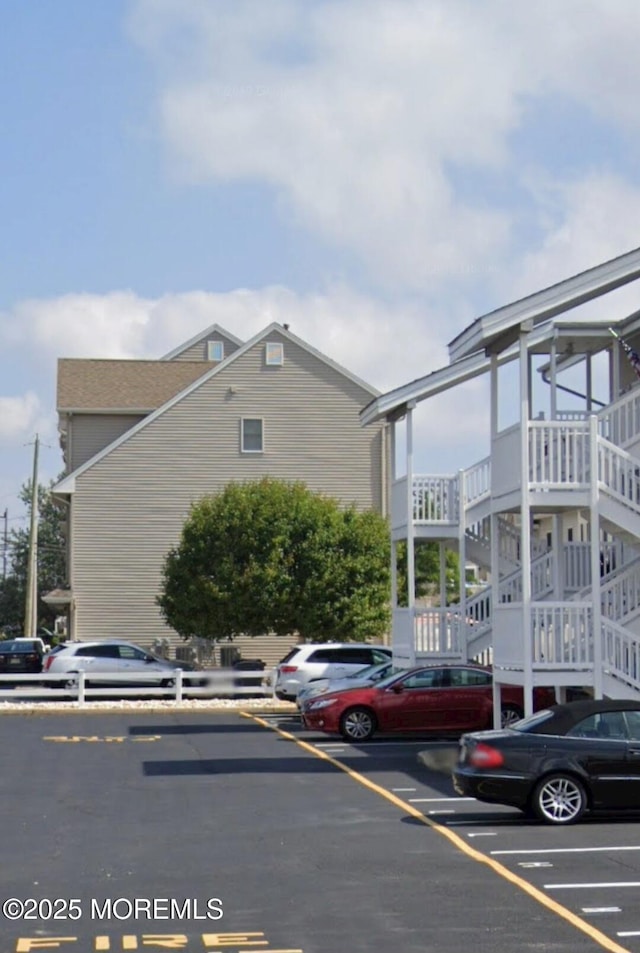 view of side of property featuring uncovered parking and stairs