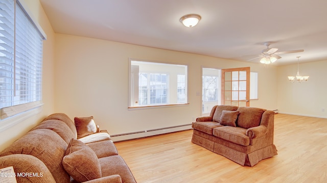 living area featuring baseboards, ceiling fan with notable chandelier, baseboard heating, and light wood finished floors