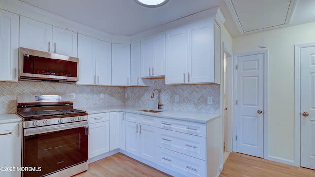 kitchen featuring light wood finished floors, appliances with stainless steel finishes, light countertops, and a sink