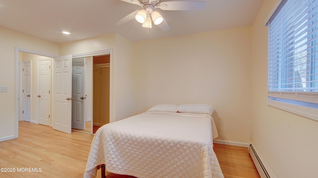 bedroom featuring ceiling fan, light wood-style floors, baseboards, and a baseboard radiator