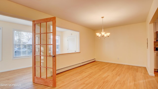 unfurnished dining area with baseboards, baseboard heating, an inviting chandelier, and light wood-style flooring