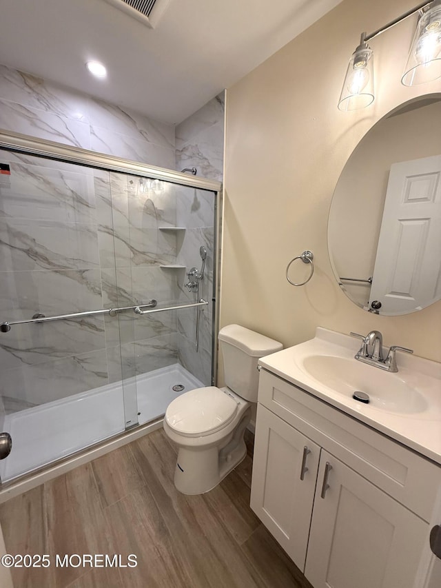 full bath with vanity, toilet, wood finished floors, and a stall shower