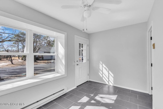 interior space featuring baseboard heating, a ceiling fan, and baseboards