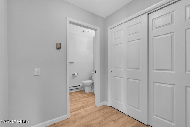 bathroom with a baseboard heating unit, baseboards, toilet, and wood finished floors