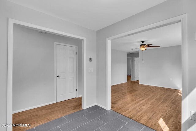 spare room featuring a ceiling fan, dark wood-style flooring, and baseboards