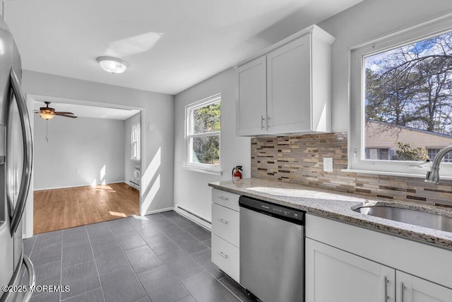 kitchen with light stone counters, stainless steel appliances, a sink, white cabinets, and tasteful backsplash