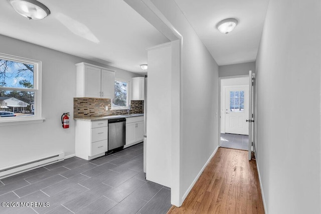 kitchen with dark wood finished floors, light countertops, stainless steel dishwasher, white cabinetry, and backsplash