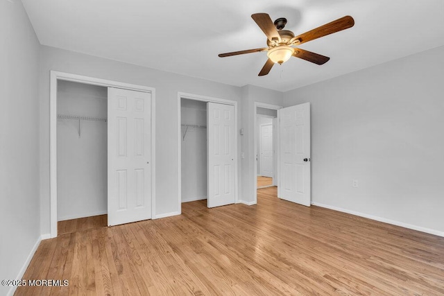 unfurnished bedroom with light wood-style floors, ceiling fan, baseboards, and two closets