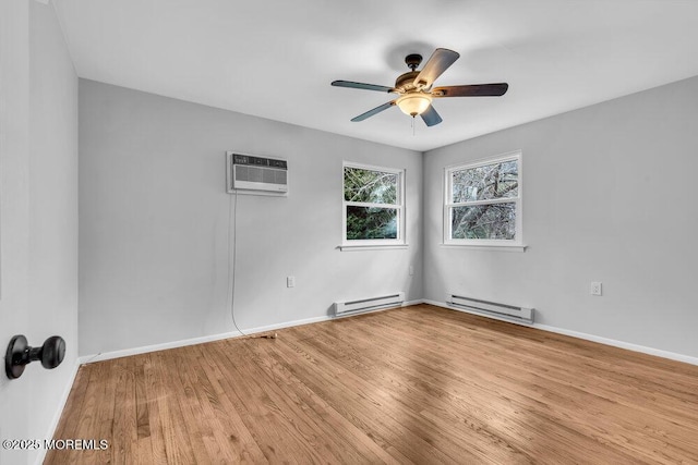 spare room with baseboard heating, wood finished floors, a ceiling fan, and baseboards