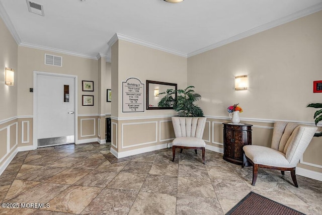 foyer entrance featuring a wainscoted wall, visible vents, a decorative wall, and ornamental molding