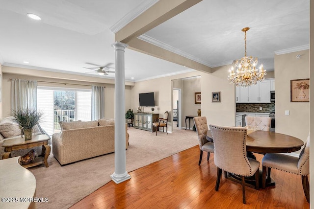 dining space featuring ceiling fan with notable chandelier, light wood-style flooring, decorative columns, and crown molding