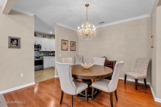 dining room featuring light wood-style flooring, baseboards, a chandelier, and crown molding