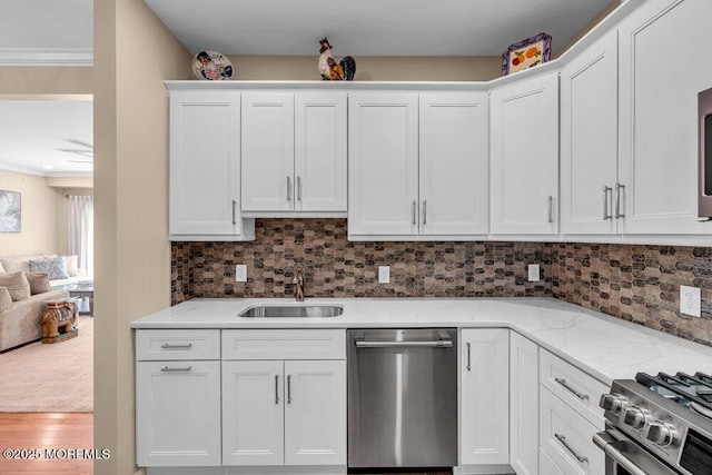 kitchen with a sink, stainless steel appliances, crown molding, white cabinetry, and backsplash