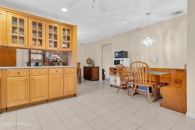 kitchen with ceiling fan with notable chandelier, white microwave, glass insert cabinets, and visible vents