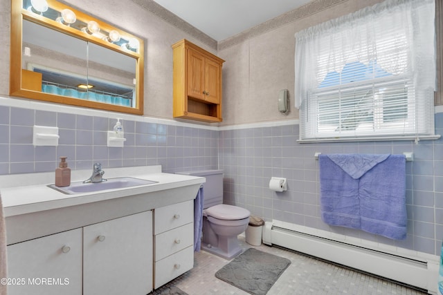 bathroom featuring tile walls, a baseboard radiator, toilet, wainscoting, and vanity