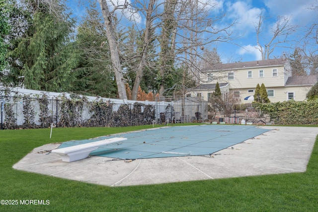 view of swimming pool with a diving board, a lawn, fence, and a fenced in pool