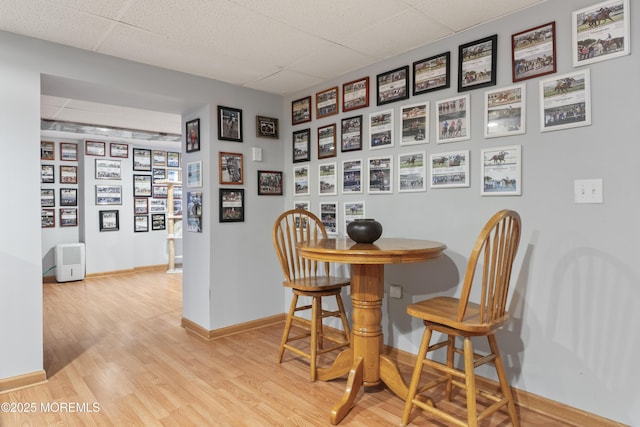 dining space featuring a paneled ceiling, baseboards, and wood finished floors